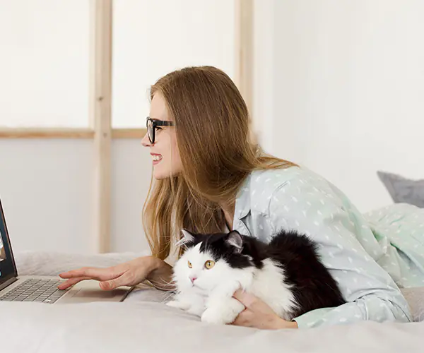 Chica junto a gato delante de un ordenador